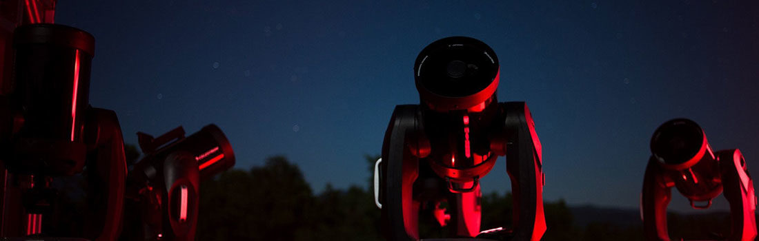 Celestron CPC 800 8-inch Schmidt-Cassegrain telescopes illuminated by red light outdoors at night