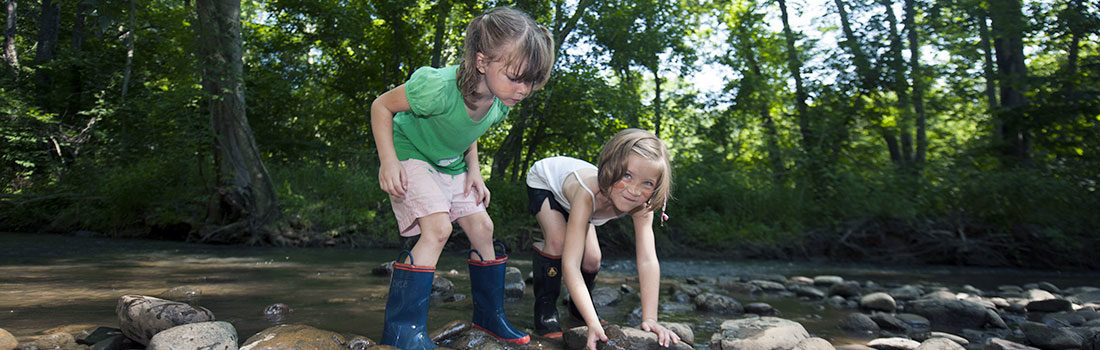 Two children standing on rocks in a river bed
