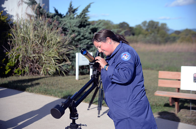 A woman looking through a telescope outdoors